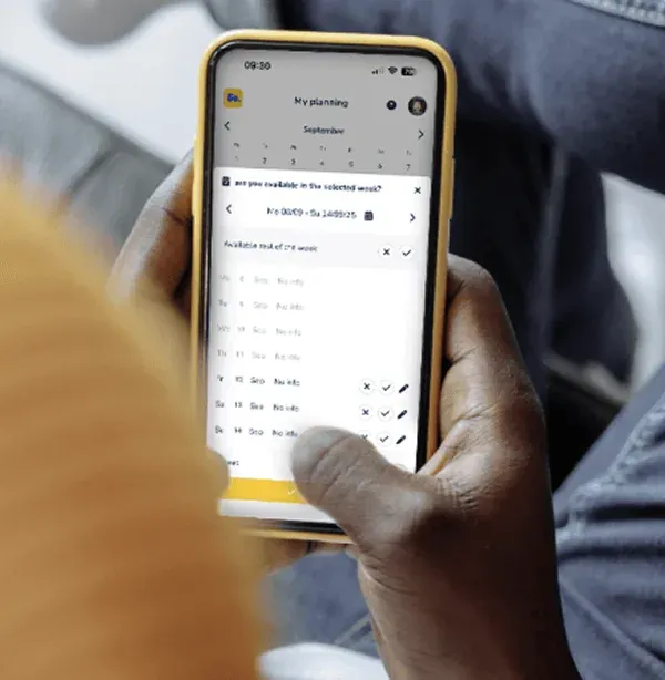 A flexi worker holding a phone with the GoTemp planning screen, setting availability for the week.