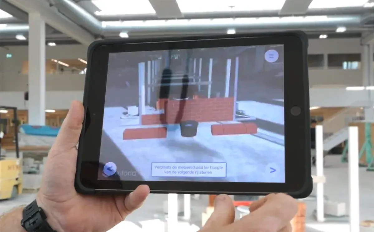 Tablet showing AR masonry instructions overlaid on a practice brick wall.